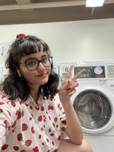 Leslie giving peace sign in front of washing machine