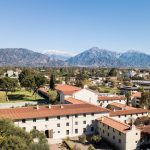 drone shot of Pomona's campus with blue skies and mountains in background